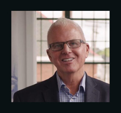 photo of Ben Guess, man with white hair and glasses wearing a blue shirt and gray suit coat