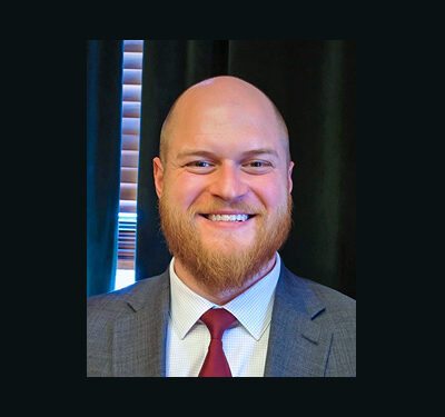 photo of Collin Marozzi, man with beard, wearing a blue checked shirt, red tie and gray blazer