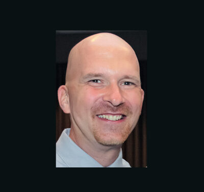 photo of Gary Daniels, man with bald head and mustache wearing a blue collared shirt