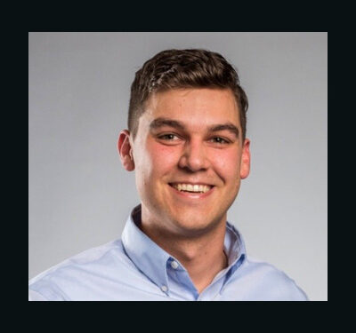 Photo of Patrick Higgins, man with short brown hair wearing a blue shirt