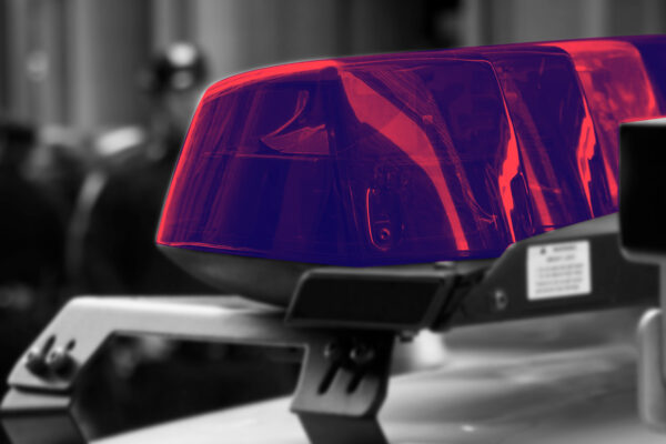 Police car lights with a navy and red color overlay, with a black and white blurry background