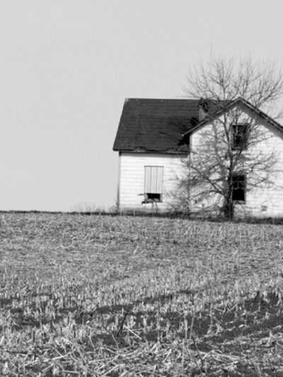 black and white photo of a white farm house in a field
