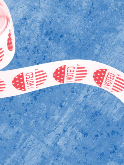 Spool of 'I Voted' stickers with a red and white color overlay on a textured blue background