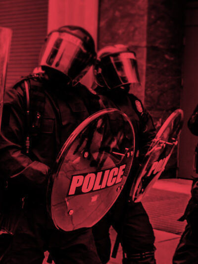 Photo of militarized police in riot gear with a black and red color overlay