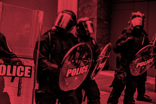 Photo of militarized police in riot gear with a black and red color overlay