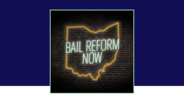 'Bail Reform Now' neon sign on a black brick background