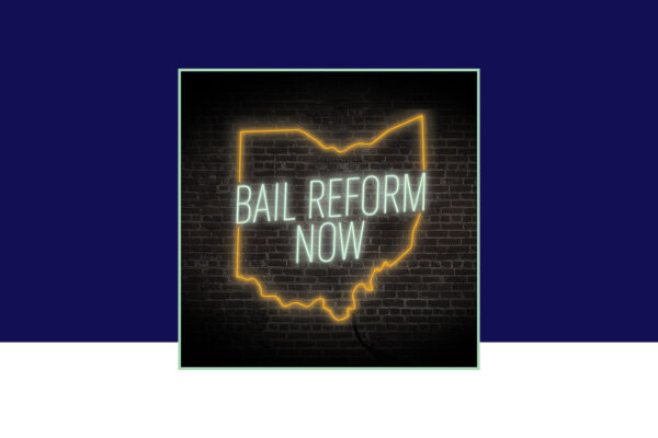 'Bail Reform Now' neon sign on a black brick background