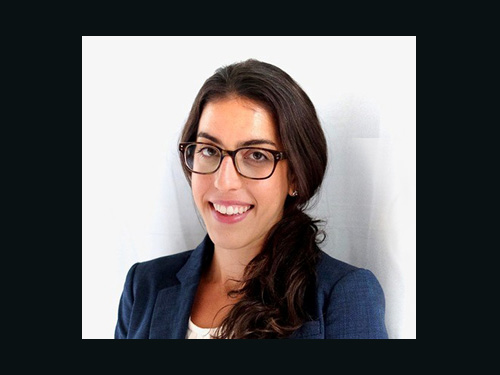 Posed portrait of Amy Gilbert, women, long brown hair pulled to the side, wearing a white shirt, blue blazer and glasses.
