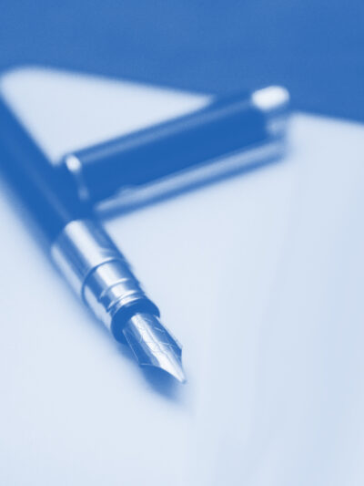 Pen with the cap off, laying on a peice of paper with a blue and white color overlay