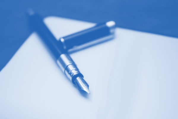 Pen with the cap off, laying on a peice of paper with a blue and white color overlay
