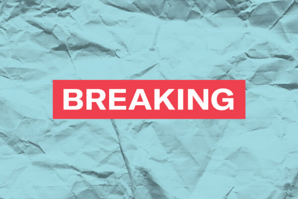 The word 'Breaking' in white font in a red rectangle on a paper textured azure background