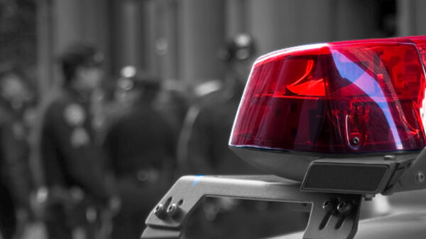 Photograph of a police siren, with police officers in the background depth of field