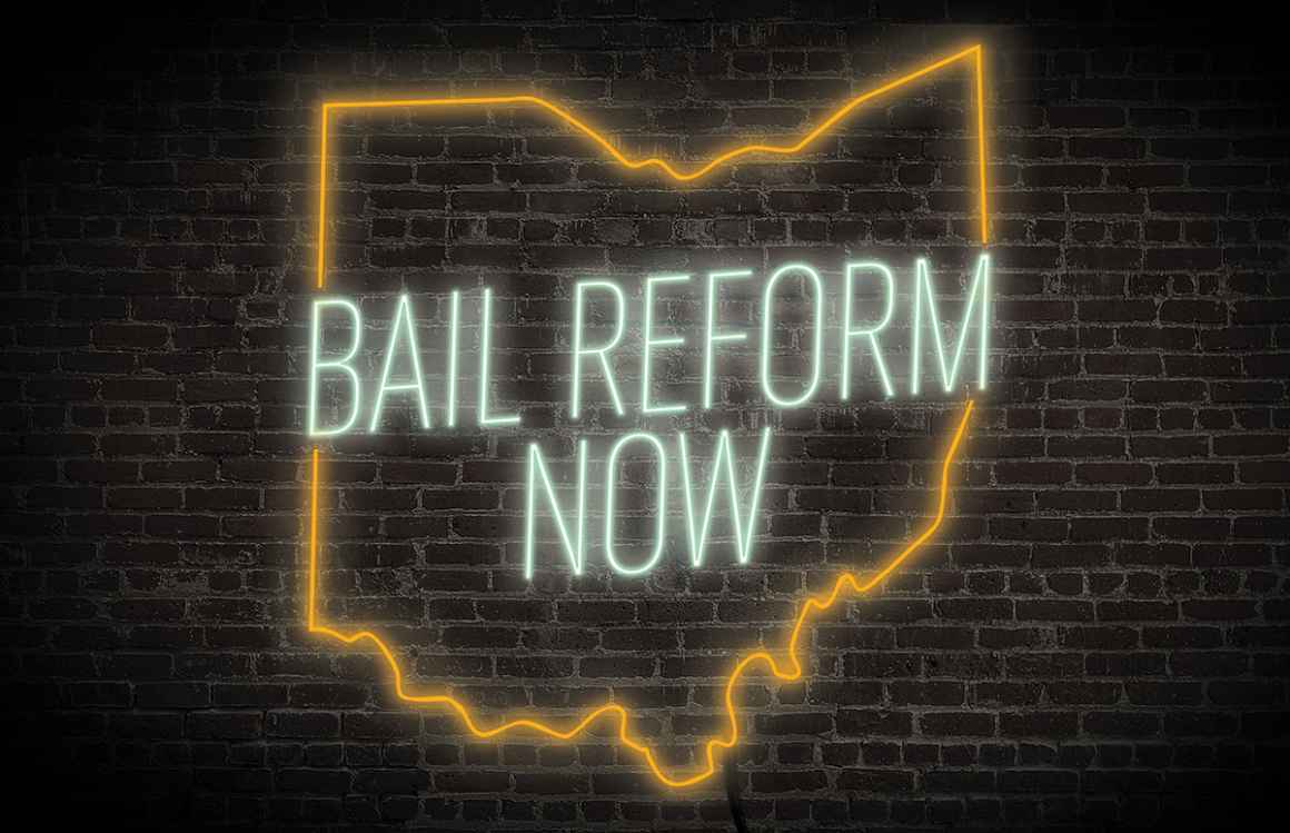 Bail Reform Now neon sign with the ourline of ohio in green and orange on a dark brick background