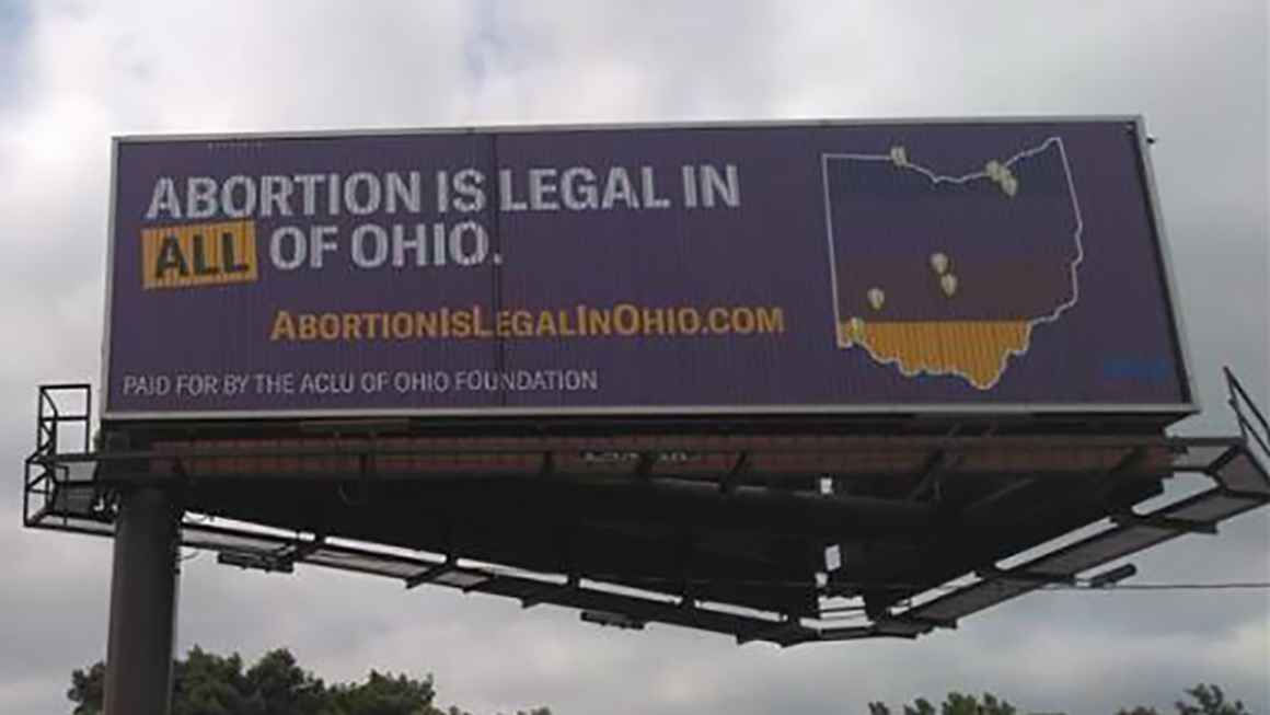 Billboard with a purple background that reads "Abortion is legal in ALL of Ohio" and includes an image of the state of Ohio with map markers showing existing abortion clinics