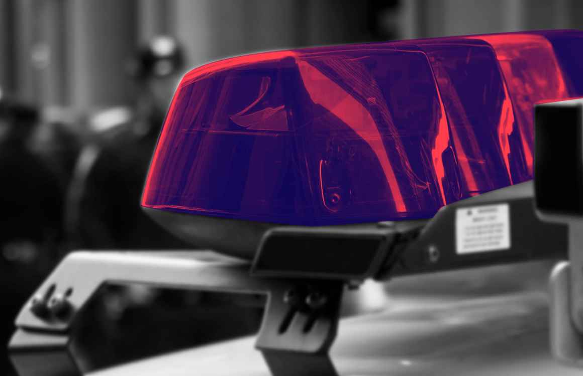 Police car lights with a navy and red color overlay, with a black and white blurry background