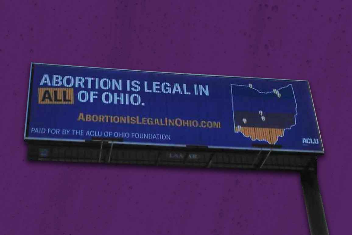 A billboard stating 'Abortion is legal in all of Ohio' with the state of Ohio on a purple textured background