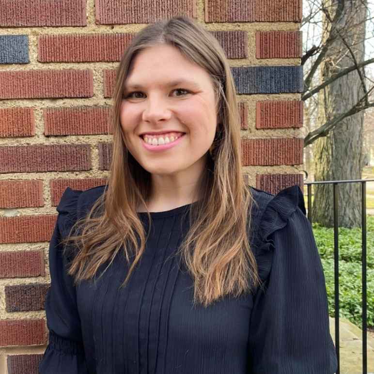 Image of woman in black shirt standing in front of a brick wall