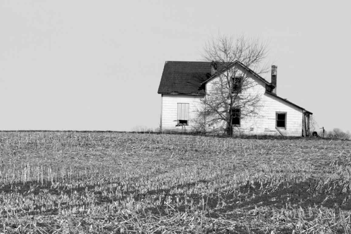 black and white photo of a white farm house in a field