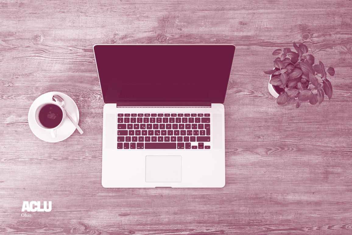 Laptop computer, a cup of coffee, and a small notepad and pen on a desk with maroon and white color overlay