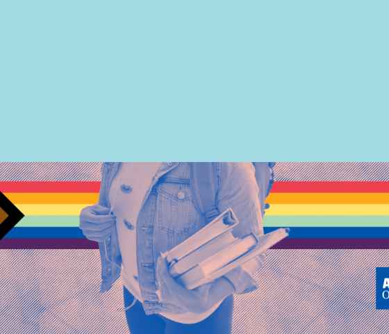 student holding books with pride flag in the background