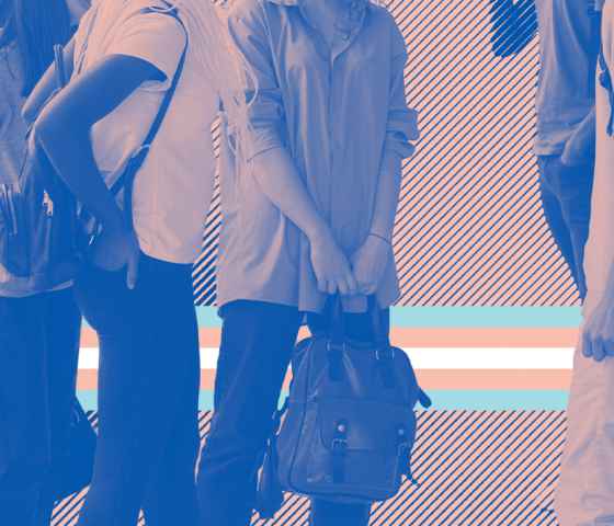 A group of young people standing with backpacks with a trans flag behind thir legs